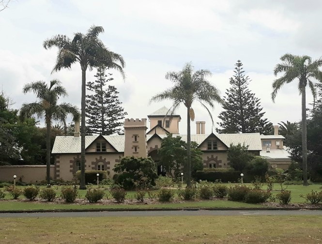 an image of a white Inn with trees and a garden in the foreground