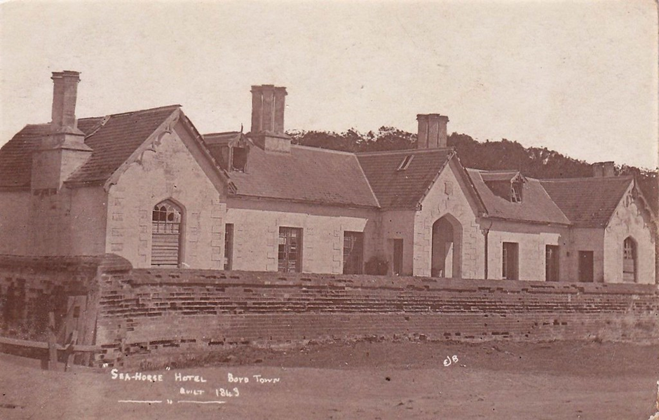 a black and white image of a white inn behind a brick wall